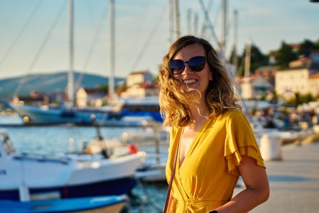 woman-in-yellow-dress-walking-down-sunny-promenade-2025-03-16-09-11-15-utc